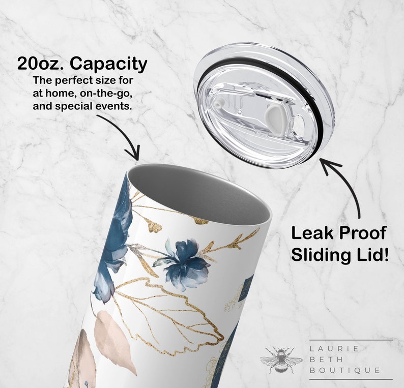 May include: A 20 ounce stainless steel tumbler with a white background and a floral design in shades of blue and gold. The tumbler has a clear, leak-proof sliding lid. The text "20oz. Capacity" and "Leak Proof Sliding Lid!" are visible in the image.