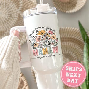 May include: White stainless steel tumbler with a floral design and the text "LOVE THEM. RAISE THEM KIND, WATCH THEM GROW" and "MAMAW megan haley".