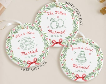May include: Three round white ceramic ornaments featuring green leaf wreaths with red berries and red bows. Each ornament displays custom names, the word Married, a date, and illustrations of wedding rings, a car, or a tiered cake.