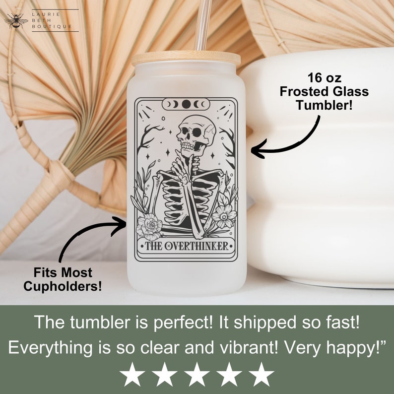 May include: A 16 ounce frosted glass tumbler with a black and white illustration of a skeleton with the text "The Overthinker" on a white background. The tumbler has a bamboo lid and a straw.