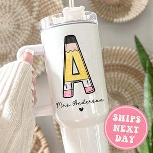 May include: White stainless steel tumbler with a black and yellow pencil design that says "A" and "Mrs. Anderson" with a small heart.