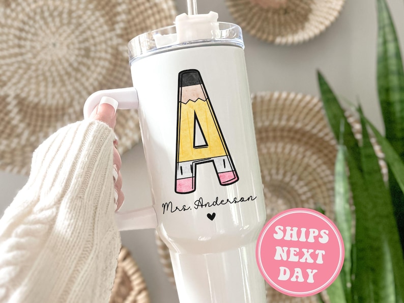 May include: White stainless steel tumbler with a black and yellow pencil design that says "A" and "Mrs. Anderson" with a small heart.