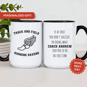 May include: Two white ceramic mugs with black handles and black rims. The mug on the left has a black and white illustration of a running shoe with wings and the text "Track and Field Running Ravens". The mug on the right has the text "If at first you don't succeed, try doing what Coach Andrew told you to do the first time".