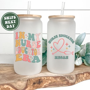 May include: Two frosted glass tumblers with bamboo lids and straws. One tumbler features the text "In My Nurse Educator Era" in colorful retro lettering. The other tumbler has a pink heart with a stethoscope and the text "Nurse Educator Megan".