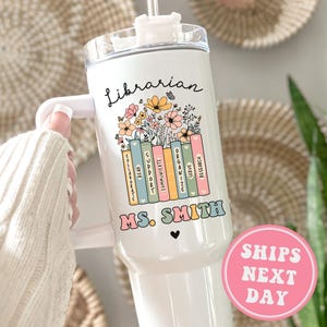 May include: White tumbler with a black and white design of a stack of books with flowers and the text "Librarian Ms. Smith".
