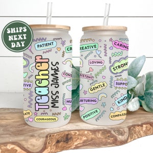 Puede incluir: Dos vasos de vidrio esmerilado con tapas de bamb&uacute; y pajitas. Los vasos est&aacute;n decorados con palabras y dise&ntilde;os coloridos, incluyendo "Teacher" y "Miss James".