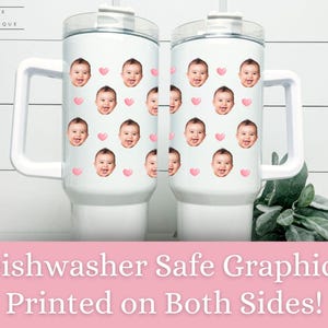 Peut inclure: Deux tasses de voyage en acier inoxydable blanc avec une poign&eacute;e et un couvercle. Les tasses sont recouvertes d'un motif de c&oelig;urs roses et de visages de b&eacute;b&eacute;s. Le texte "Dishwasher Safe Graphics Printed on Both Sides!" est imprim&eacute; sur une banni&egrave;re rose sous les tasses.