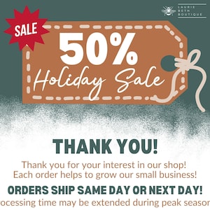 May include: A brown rectangular tag with white dashed borders and a string, featuring the text 50% Holiday Sale in white. A red starburst icon with the word SALE is in the corner. The Laurie Beth Boutique logo with a bee icon is at the top right.
