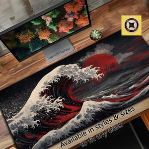 Puede incluir: Alfombrilla de escritorio con un diseño de ola japonesa y un gran sol rojo. La alfombrilla es negra con detalles en blanco y rojo. El texto en la parte inferior dice "Available in styles & sizes to fit any desk".