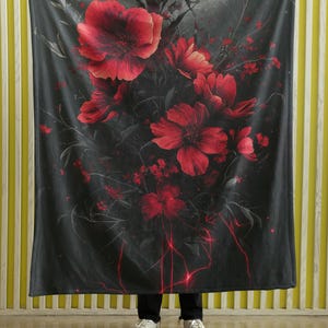 May include: A black and gray throw blanket with a red floral pattern. The blanket features a dark background with red flowers and vines.