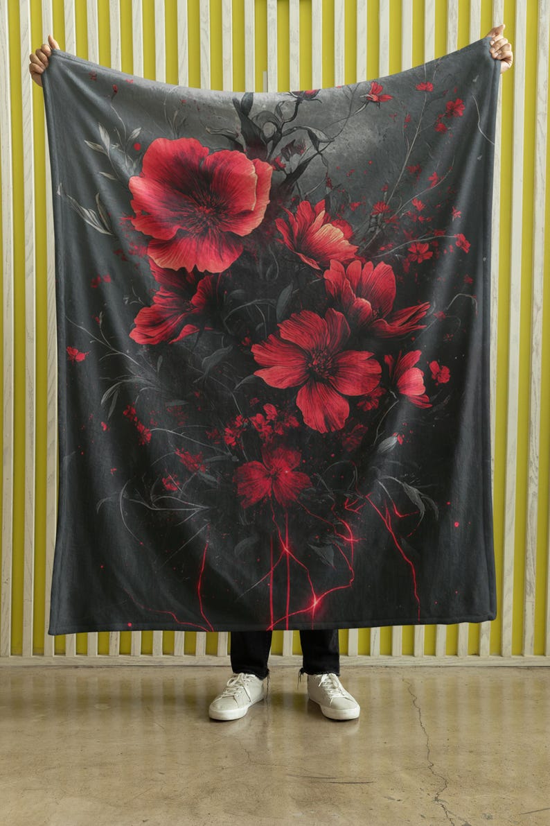 May include: A black and gray throw blanket with a red floral pattern. The blanket features a dark background with red flowers and vines.