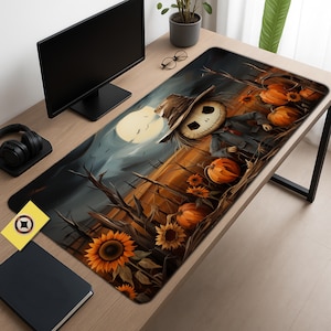 May include: A large rectangular desk mat featuring a Halloween-themed design. The artwork depicts a scarecrow with a skull-like face, pumpkins, sunflowers, and a full moon. The color palette includes shades of orange, brown, and blue.