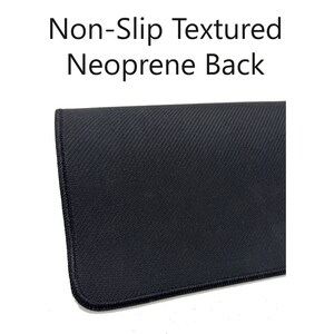 May include: Close-up of the black, textured, non-slip neoprene backing of a mouse pad. The backing is designed to prevent the mouse pad from sliding on a desk.