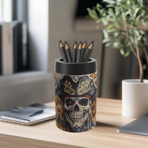 May include: Black pencil holder featuring a skull and crossbones design. The skull is wearing a pirate hat and has a gold earring. The holder is filled with black pencils.