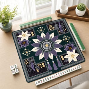 May include: A square mahjong mat featuring a dark green background with a central purple and cream floral mandala design. The mat includes corner floral accents, hanging tassel graphics, and is surrounded by green mahjong tiles and white tiles.