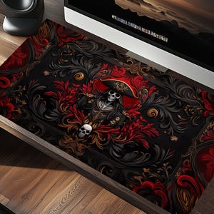 May include: A black and red gothic-style desktop mat with a skull wearing a red and gold pirate hat. The skull is surrounded by intricate floral designs and gold accents.