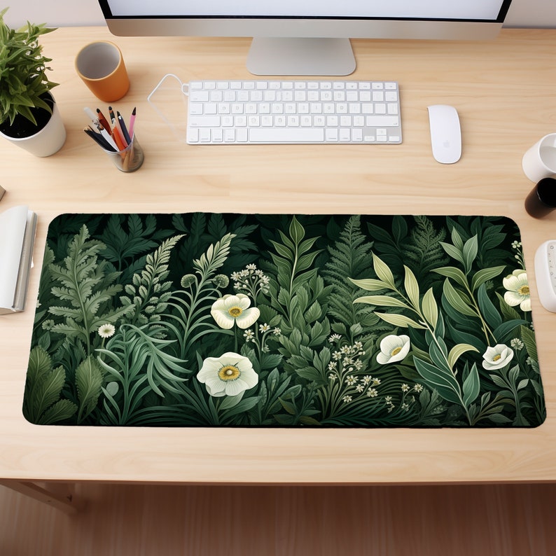 May include: A green and white floral design mousepad with a dark green background. The mousepad features white flowers and green leaves.