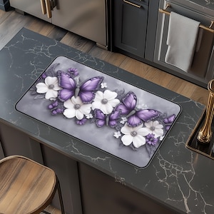 May include: Purple and white butterfly kitchen rug with a floral design. The rug has a gray background and features a row of butterflies and flowers.