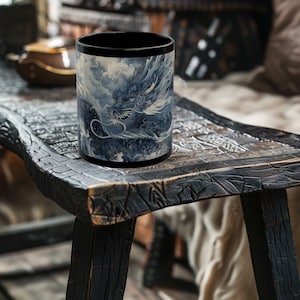 May include: Black ceramic mug with a blue and white dragon design. The dragon is depicted in a swirling cloud-like pattern.