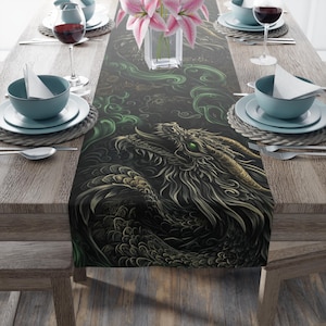 May include: A black table runner featuring a detailed illustration of a dragon with green eyes and gold accents. The dragon design is set against a backdrop of green swirls. The table is set with teal plates, wine glasses, and pink flowers.
