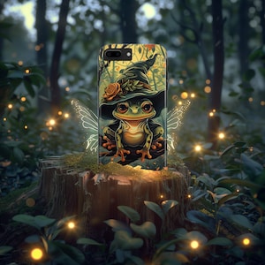 May include: A green frog wearing a witch's hat with a red flower on it. The frog is sitting on a branch with a fairy wing design behind it. The image is on a phone case.