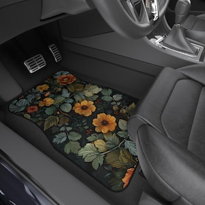 May include: A black car floor mat with a floral design featuring yellow, orange, and green flowers on a dark background.