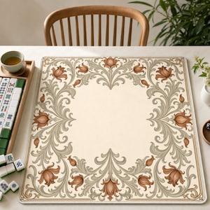 May include: A rectangular game mat featuring a cream-colored center surrounded by a decorative border of light green scrolling acanthus leaves and brown tulip-like flowers. The mat has a thin brown outline and a clean, flat surface design.