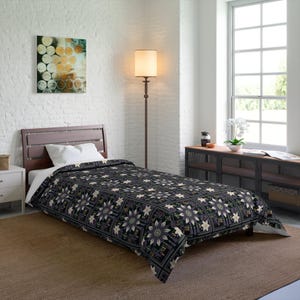 May include: A single bed featuring a dark-coloured comforter with a repeating floral pattern in shades of purple, white, and black. The bed has a wooden headboard, a white pillow, and is positioned in a room with white brick walls and a floor lamp.