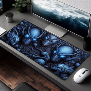 May include: A blue and black gaming mouse pad with a graphic of alien-like creatures with glowing blue eyes. The mouse pad is on a wooden desk with a computer monitor and a mouse.