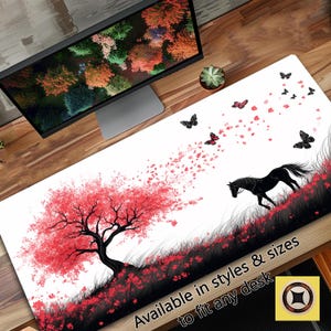 May include: A white desk mat featuring a black horse, a pink tree, and pink and black butterflies. The text "Available in styles & sizes to fit any desk" is at the bottom of the mat.