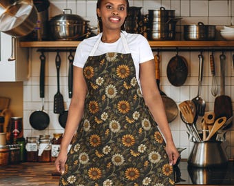 May include: A brown apron with a sunflower and floral pattern. The apron has adjustable straps and a large pocket in the front.