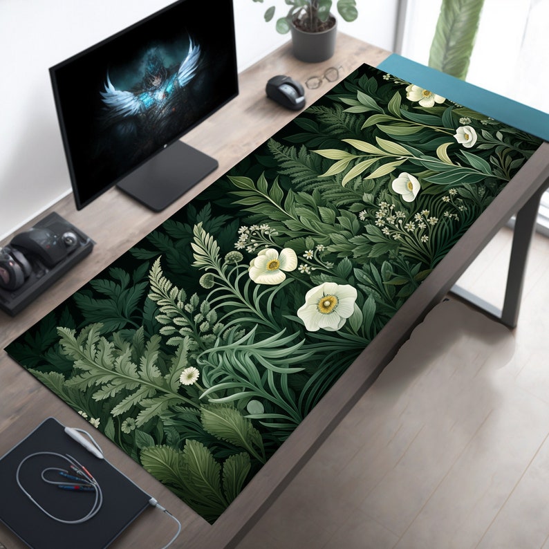 May include: A green and white floral design desk mat with a dark green background. The mat features white flowers and green leaves in a repeating pattern.