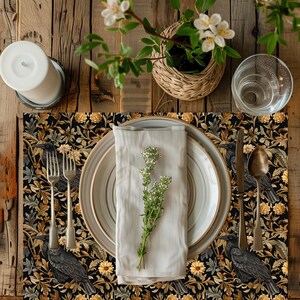Puede incluir: Un mantel individual negro y dorado con estampado floral, un plato blanco, una servilleta y cubiertos. El mantel individual presenta un patrón repetitivo de pájaros negros y flores amarillas.