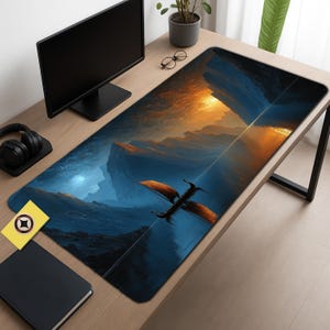 Puede incluir: Una alfombrilla de escritorio rectangular grande con un paisaje de fantasía. La obra de arte representa un dragón volando sobre el agua, con montañas y una puesta de sol en el fondo. La paleta de colores incluye tonos de azul, naranja y negro.