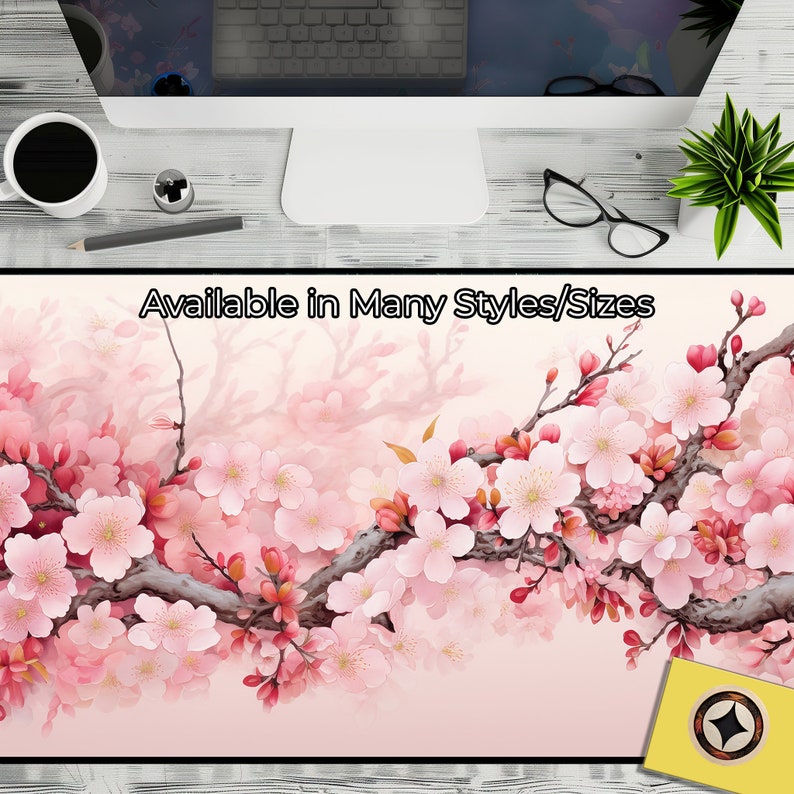 May include: A pink and white floral design with cherry blossoms on a branch. The design is on a pink background with a light watercolor effect. The text "Available in Many Styles/Sizes" is at the top of the image.