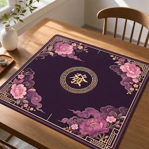 May include: A square dark purple mat featuring a central gold circular emblem with the Chinese character for prosperity. The corners are decorated with large pink peony flowers, swirling purple clouds, and gold geometric border patterns.