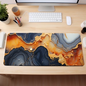May include: A large, rectangular desk mat with a swirling abstract design. The design features shades of gray, orange, and gold, resembling a marble or agate pattern.