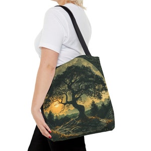 May include: A black tote bag with a design of a large tree with a full moon behind it. The tree is silhouetted against a sunset sky. The bag has a black strap.