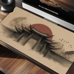 Könnte beinhalten: Beige Schreibtischunterlage mit einer asiatisch inspirierten Illustration. Das Design umfasst eine traditionelle Torstruktur, eine rote Sonne, Wolken und fliegende Vögel. Das Kunstwerk ist in Grau- und Brauntönen gehalten.