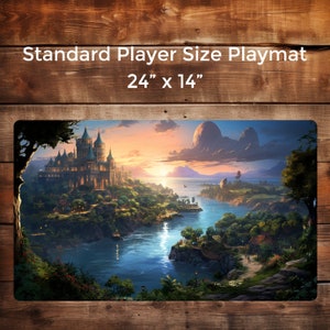 May include: A fantasy landscape with a large castle on a hill overlooking a river. The sky is a vibrant orange and pink, with clouds and a large moon in the distance. The river flows through a lush green valley, with trees and shrubs lining the banks. The castle is made of stone and has many towers and spires. This is a 24" x 14" playmat.