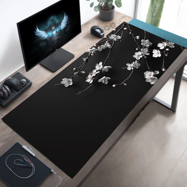 K&ouml;nnte beinhalten: Schwarze Schreibtischunterlage mit einem wei&szlig;en Blumendesign mit zarten Zweigen und Bl&uuml;ten. Die Unterlage ist aus strapazierf&auml;higem, rutschfestem Material gefertigt und sch&uuml;tzt perfekt die Oberfl&auml;che Ihres Schreibtisches.