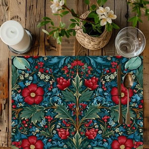 Può includere: Un sottopiatto floreale con sfondo blu scuro e motivo di fiori rossi, foglie verdi e bacche. Una candela, un bicchiere, un cucchiaio e un coltello sono su un tavolo di legno. Un piccolo cestino con fiori bianchi è anche sul tavolo.