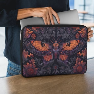 May include: A black laptop sleeve with a zipper closure features a colorful moth with orange and purple wings surrounded by dark floral patterns.
