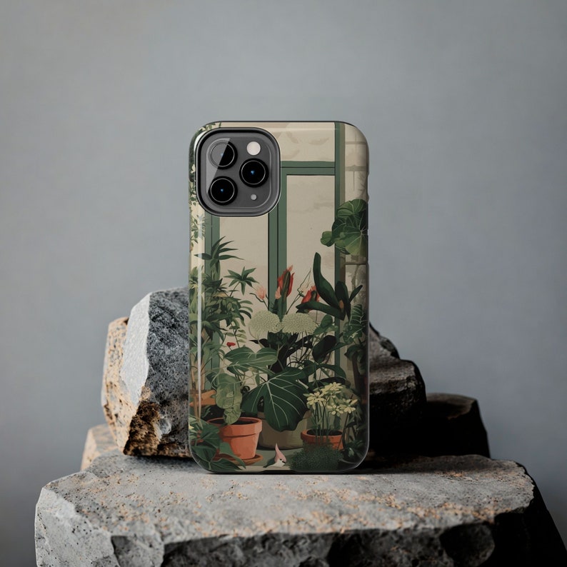 May include: A phone case featuring a green, brown and white botanical illustration of plants in a greenhouse. The case has a black border and a camera cutout.