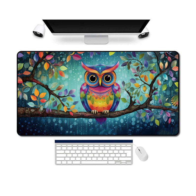 May include: A rectangular mouse pad featuring a colorful owl perched on a tree branch. The owl has vibrant blue, yellow, orange, and purple feathers. The background is a teal color with colorful leaves.