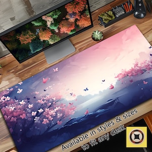 Puede incluir: Una alfombrilla de escritorio larga y rectangular con un paisaje de acuarela con flores de cerezo rosas, mariposas y un cielo suave en gradiente. La alfombrilla tiene una base azul oscuro y el texto "Available in styles & sizes to fit any desk".
