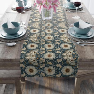 May include: A blue and white table runner with a floral and butterfly pattern. The runner is laid out on a wooden table with place settings on either side.