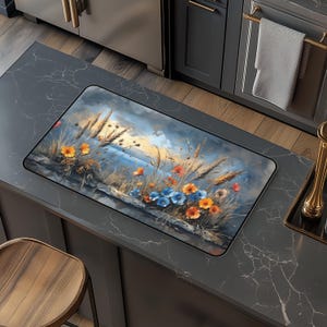Puede incluir: Una alfombra de cocina con un diseño floral colorido con flores azules, naranjas y amarillas sobre un fondo azul y marrón. La alfombra presenta un paisaje marítimo con una puesta de sol en el fondo.