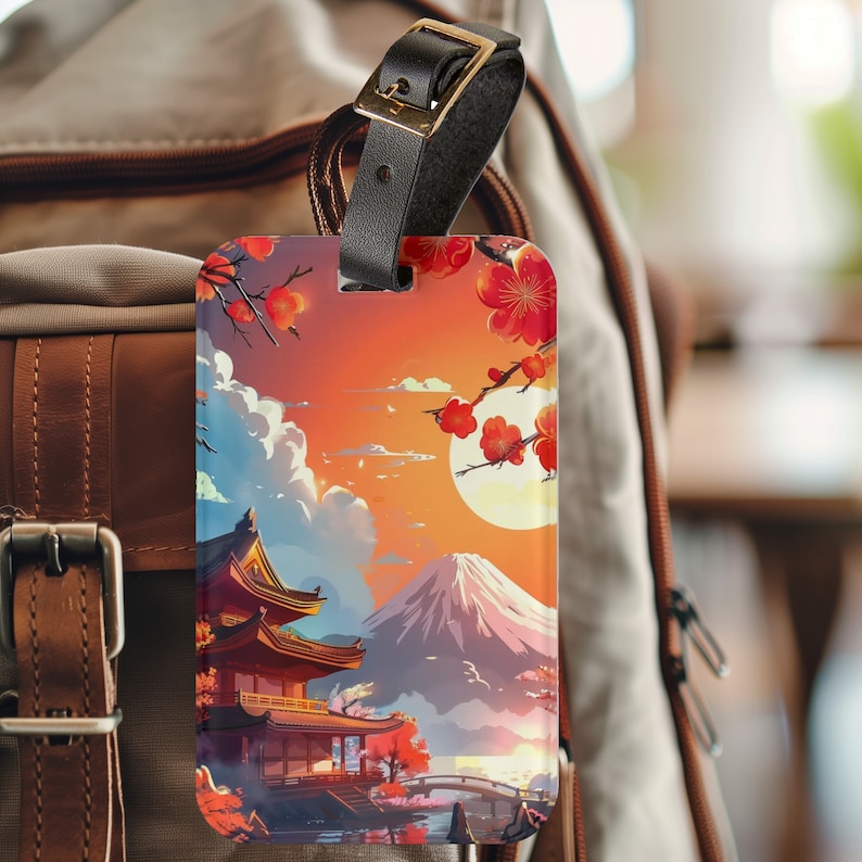 May include: A luggage tag with a colorful illustration of a Japanese temple, Mount Fuji, and cherry blossoms. The tag is attached to a brown leather strap.