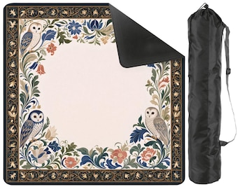 May include: A square outdoor blanket featuring a cream-colored center and a decorative border with owls, blue and orange flowers, and green foliage. The blanket has a black underside and comes with a black cylindrical carrying bag with a strap.